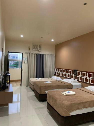 a hotel room with three beds and a television at Zion Pension House in Ozamis