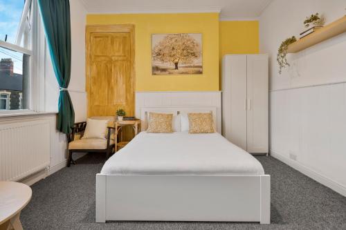 a bedroom with a white bed and a yellow wall at Cardiff City Guesthouse, Central Rooms, Fast Wi-Fi, On-Street Parking in Cardiff