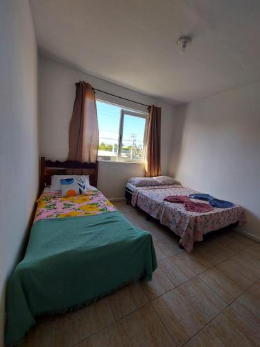 a bedroom with two beds and a window at Pousada recanto das ondas in Macaé