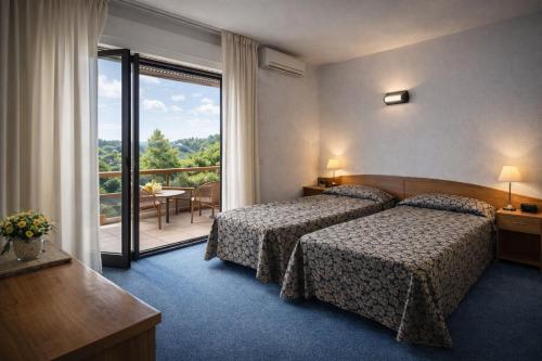 a hotel room with two beds and a balcony at Hotel Granducato in Montepulciano