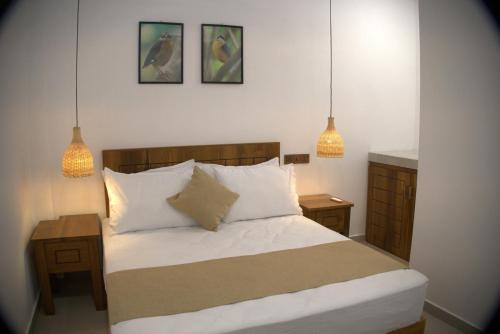 a bedroom with a bed and two pendant lights at Nest & Rest in Sri Jayewardenepura Kotte