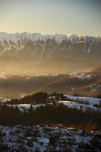 a snow covered mountain range with a town in the foreground at The Pines Bucegi Lodge in Bran