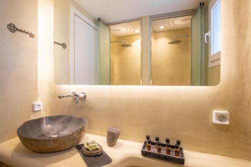 a bathroom with a sink and a large mirror at ĪKADE Mykonos in Mikonos
