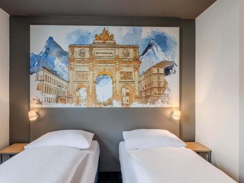 two beds in a room with a painting on the wall at B&B HOTEL München-Schwabing in Munich