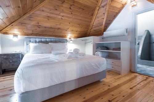 a bedroom with a large white bed with wooden ceilings at Pelion Villa Serenity View in Pouríon