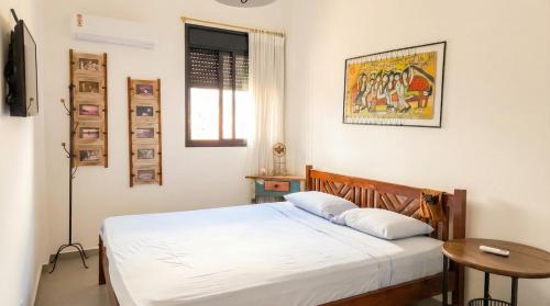a bedroom with a white bed and a table at Apartamento do Paulão in Ubatuba