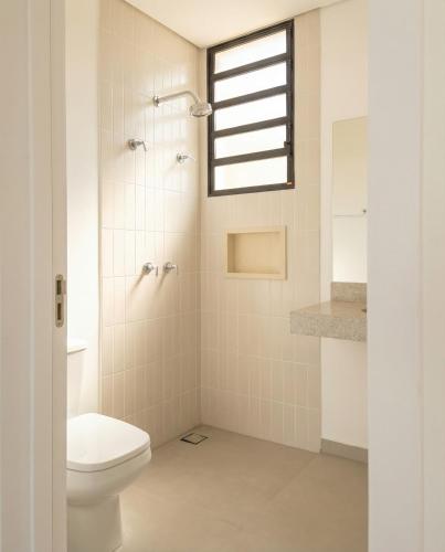 a bathroom with a toilet and a window at Apartamento do Paulão in Ubatuba