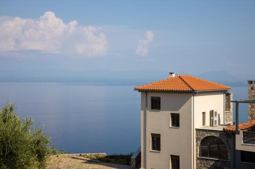 a white building with an orange roof next to the water at Searocks Exclusive Village in Kalamata