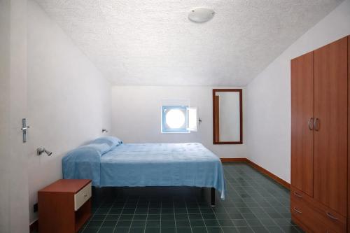 a bedroom with a blue bed and a window at La Mansarda Navarrese in Santa Maria Navarrese