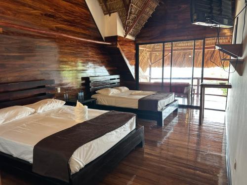 two beds in a room with wooden walls at Hotel Bahía in Marisco Guapinol