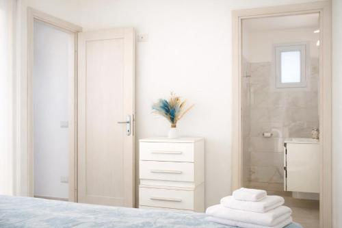 a white bedroom with a bed and a bathroom at Residenza Sa Olia in Budoni