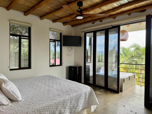 a bedroom with a bed and a balcony with windows at Finca Campestre Colibrí in Quebradanegra