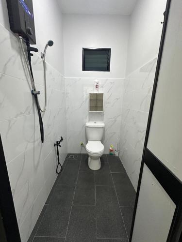 a bathroom with a toilet and a television in it at Homestay Khan in Arau