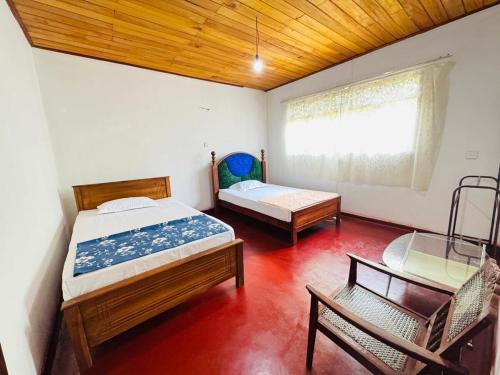 a bedroom with two beds and a chair and a window at Nihal Villa in Weligama