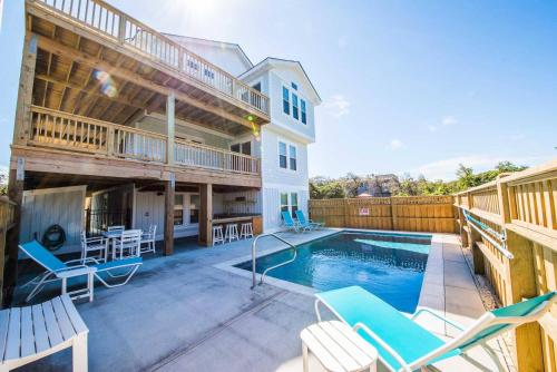 a house with a swimming pool and a deck at Sea Fever - Duck, Saltaire, 130 Yds to Beach, Ocean View, Pool, Hot Tub, Tiki Bar, Flex Stays in Duck