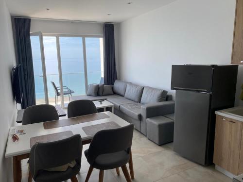a living room with a couch and a table and chairs at Ocean View Beach Apartment in Shëngjin
