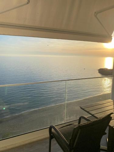 a chair sitting in front of a window looking at the ocean at Ocean View Beach Apartment in Shëngjin
