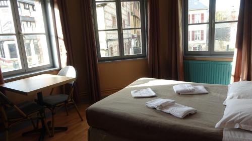 a bedroom with a bed and a desk and windows at L'Hôtel de la Taverne in Étretat