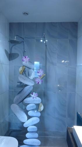 a shower with rocks and flowers on a wall at L'Hôtel de la Taverne in Étretat