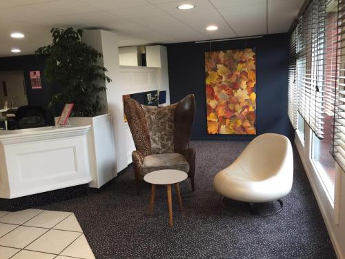 a waiting room with a chair and a table and a chair at Hostellerie Saint Vincent Beauvais Aeroport in Beauvais