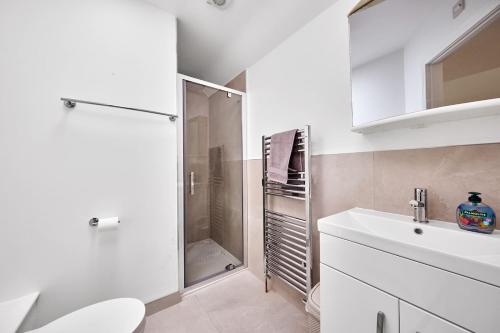 a white bathroom with a shower and a sink at Cappaghmore by Escape Ordinary in Portstewart