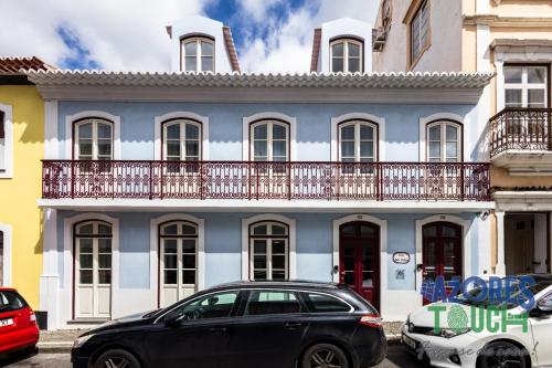 a black car parked in front of a blue and white building at Hostel Casa São Pedro in Angra do Heroísmo