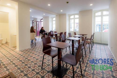 a restaurant with tables and chairs and people sitting at tables at Hostel Casa São Pedro in Angra do Heroísmo