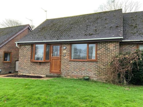 a brick house with a door and a yard at Daisy Cottage in Polegate