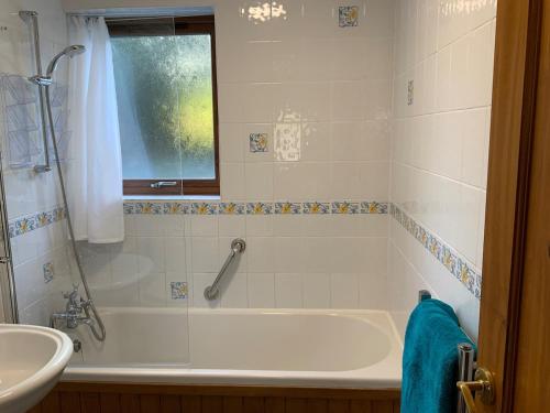 a bathroom with a bath tub and a sink at Daisy Cottage in Polegate