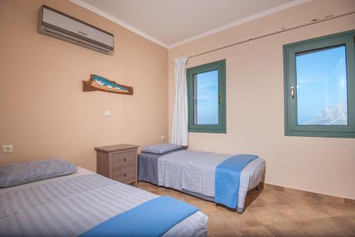 a bedroom with two beds and two windows at Sky & Sea View Retreat in Telendos