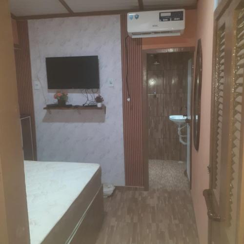 a bedroom with a bed and a television on the wall at Sereia beach chalé in Icapuí