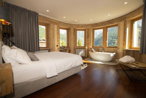 a bedroom with a bed and a bath tub and windows at Grey Castle garnì&suite in Ponte di Legno