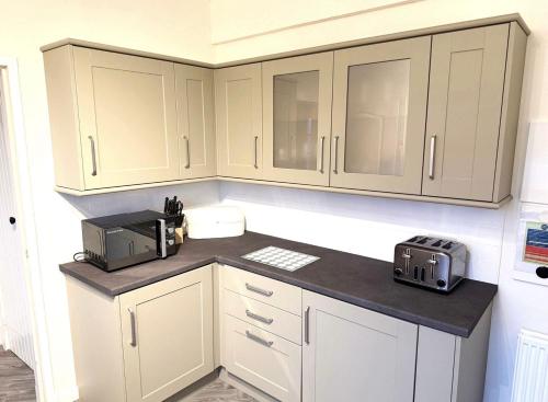 a kitchen with white cabinets and a counter top at Balmoral Residence 30 mins from Edinburgh and Glasgow in Falkirk