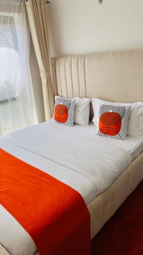 a bed with orange and white pillows and a window at Tusmo homes in Ongata Rongai 