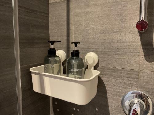 a white holder with two bottles of soap in a bathroom at Ripalta House in San Donato Milanese