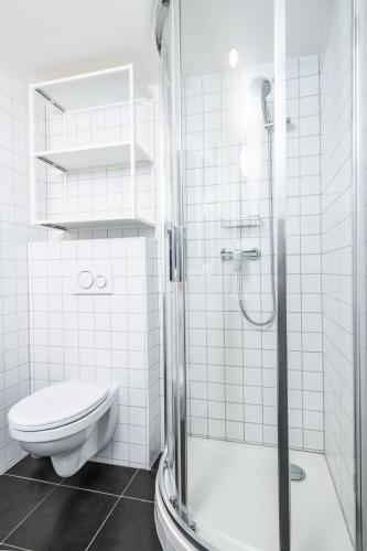 a white bathroom with a toilet and a shower at Kolonie Apartments in Žabovřesky