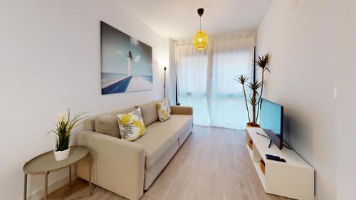 a living room with a couch and a tv at Bretón 17- Apartamentos con piscina climatizada en Alicante centro in Alicante