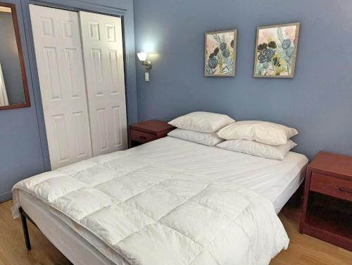 a bedroom with a white bed and two pictures on the wall at Lakepoint Cottage Resort in Killaloe Station