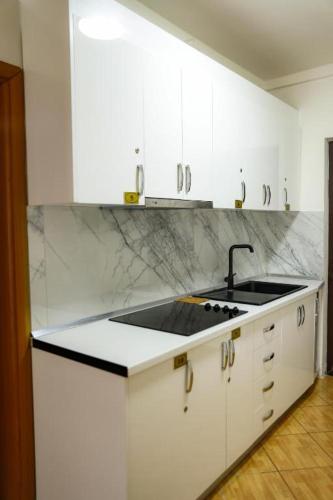 a kitchen with white cabinets and a sink at Hotel Blu Mare Shengjin in Shëngjin