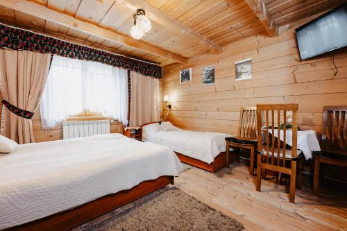 a bedroom with two beds and a flat screen tv at Pokoje u Gronicki in Bukowina Tatrzańska