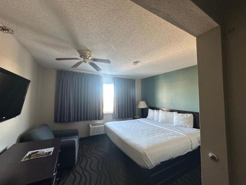 a hotel room with a bed and a ceiling fan at Baymont Inn & Suites by Wyndham Lincoln NE in Lincoln