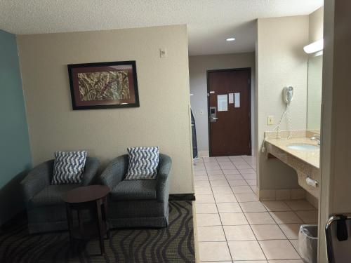 a hotel room with two chairs and a sink at Baymont Inn & Suites by Wyndham Lincoln NE in Lincoln
