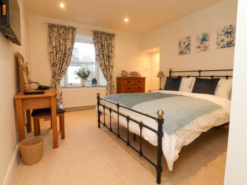a bedroom with a bed and a desk and a window at Cobble Cottage in Clitheroe