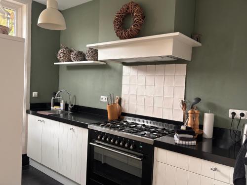 a kitchen with a black stove and white cabinets at Next To Sea in Vlissingen