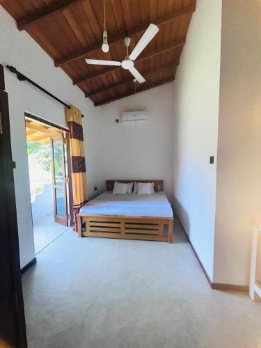 a bedroom with a bed and a ceiling fan at Sunil VIlla in Talpe