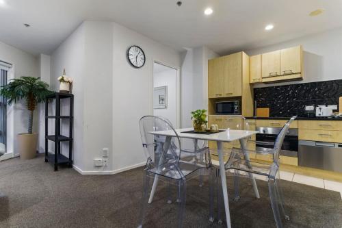 a kitchen with a table and chairs and a clock on the wall at Central Abode with Free Parking - Skyline views in Auckland