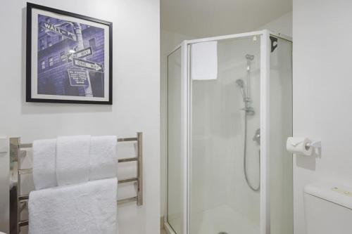 a white bathroom with a shower and a toilet at Central Abode with Free Parking - Skyline views in Auckland