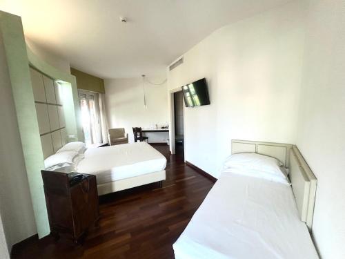 a hotel room with two beds and a desk at Best Western Cesena Hotel in Cesena
