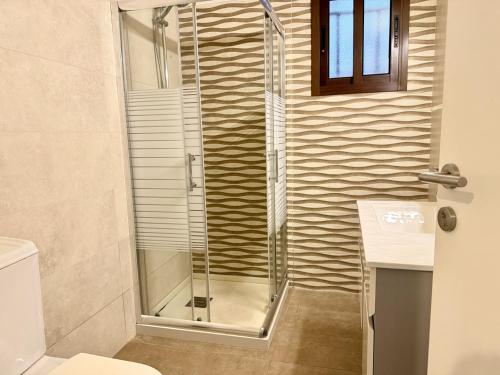 una doccia con una porta in vetro in un bagno di Pearl a Al Ḩulwah