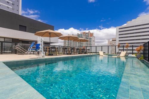 a swimming pool with chairs and umbrellas on a building at All Batel - Suyts in Curitiba